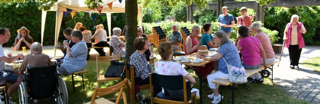 Das Bild zeigt fröhliche Menschen beim Kaffeetrinken im Freien.